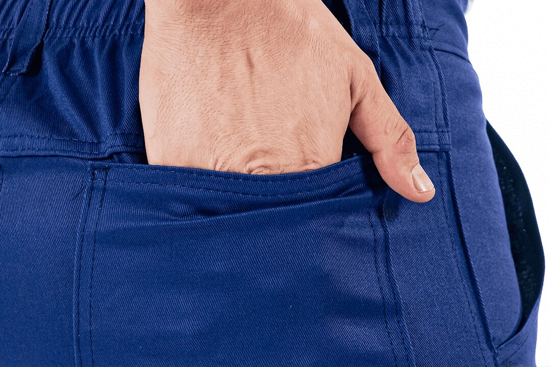 Close em uma mão dentro do bolso de uma calça azul feita de tecido brim.